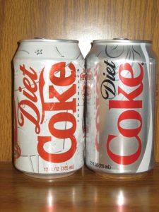 Two cans of Diet Coke next to each other. One has an older design and one has a newer design.