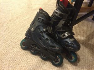 A pair of rollerblades set down on a floor.