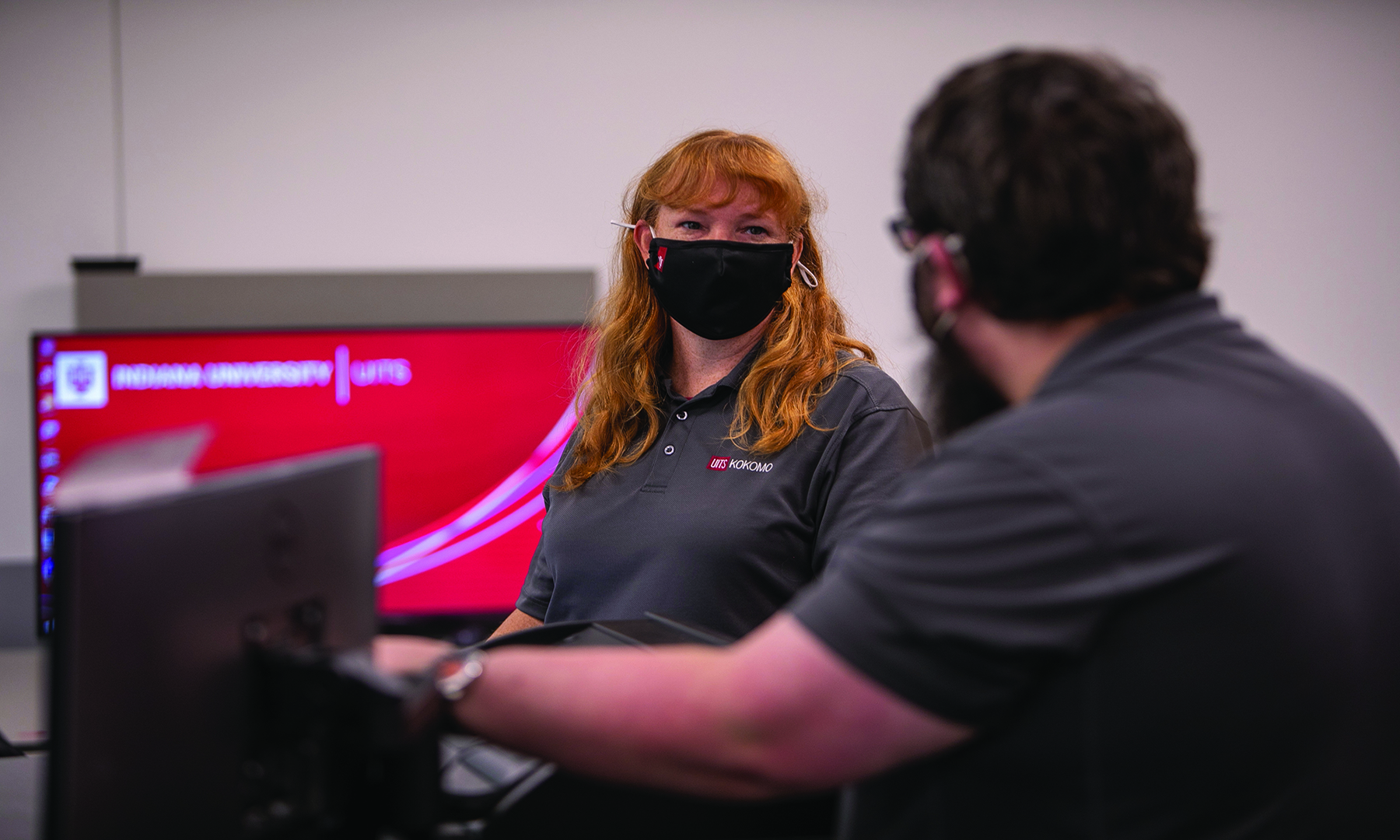 female and male wearing masks working on a computer