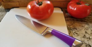 knife on cutting board with tomato