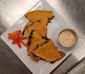 vegetarian quesadilla on plate with dipping sauce and red pepper garnish