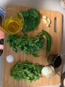 parsley, mint, and cilantro along with oil and garlic on a cutting board