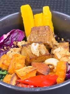 bowl with tofu, sweet potato, peppers, cashews, and mango